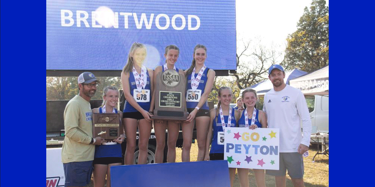 xc girls team posing with championship trophy